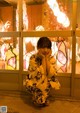 A woman in a kimono sitting in front of a window.